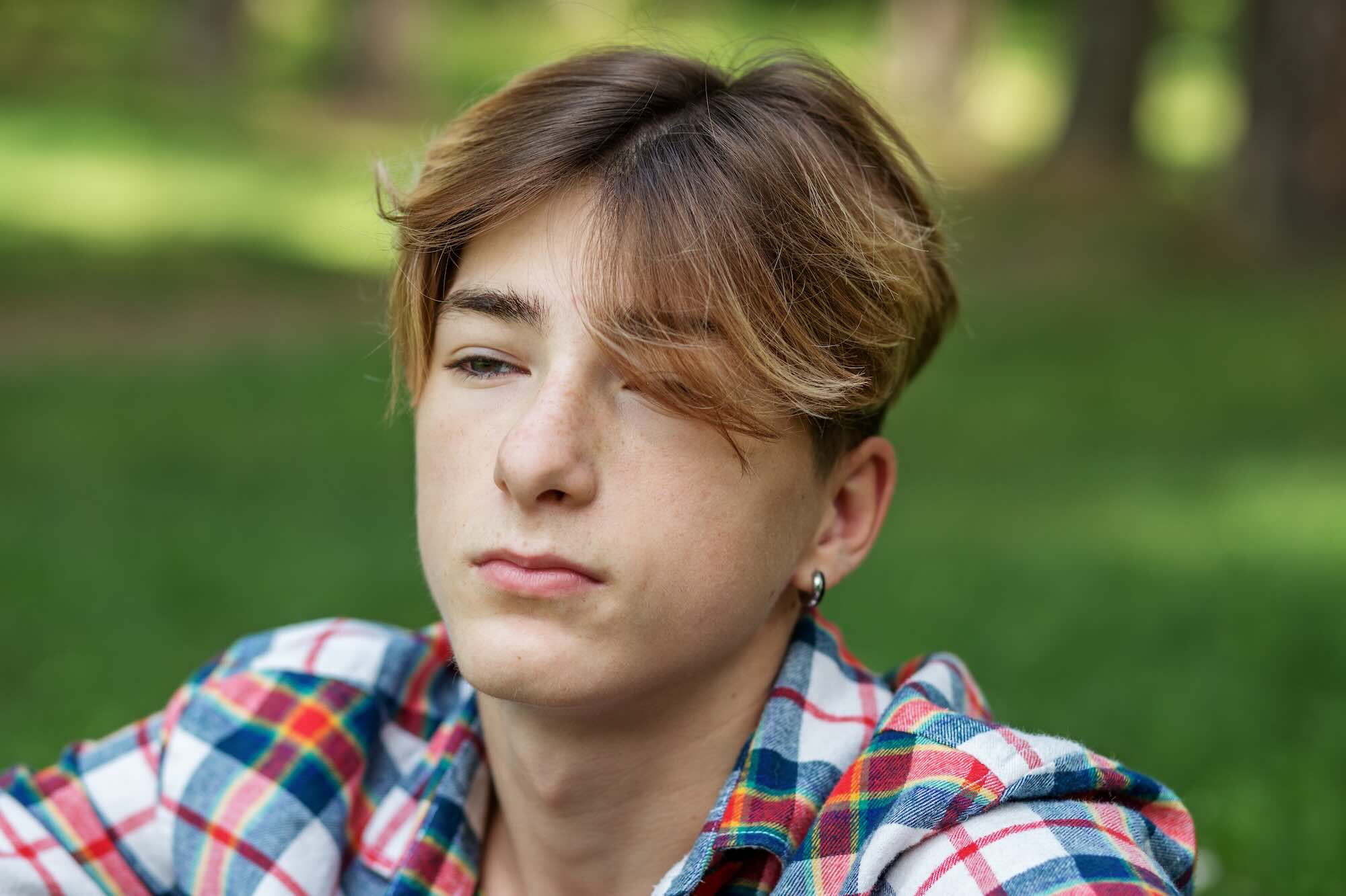 Close-up portrait of a teenager boy outdoors. Gen Z. Identity development. Unhappy and stress.