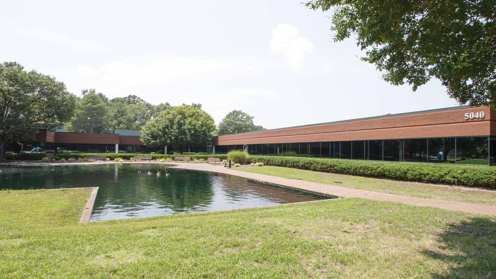 there is a pond in front of a building with a walkway