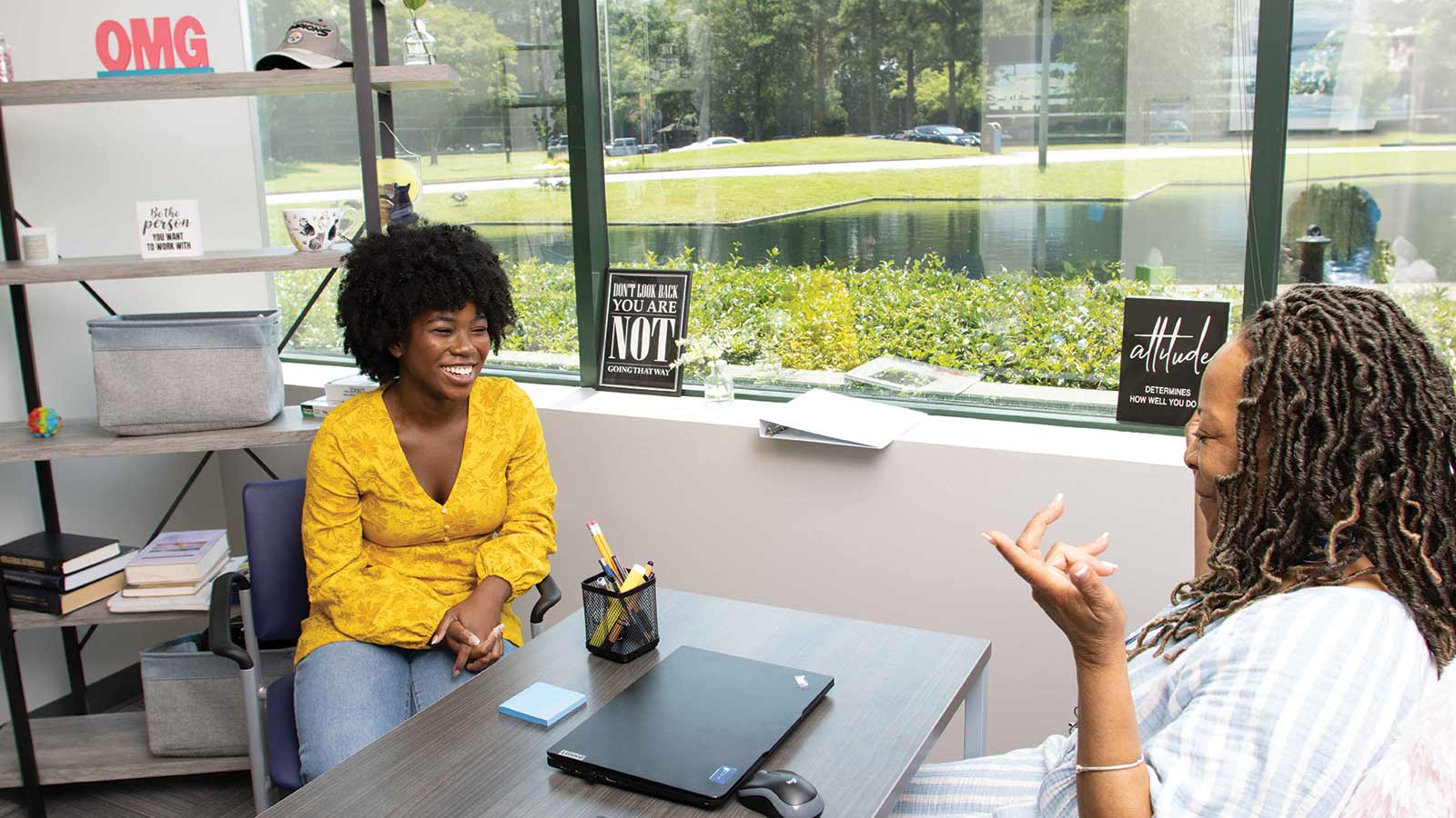 there are two women sitting at a table talking to each other