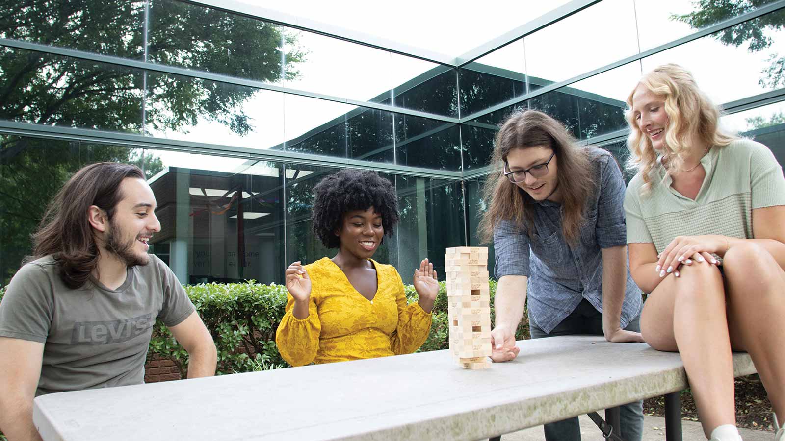 three women and a man sitting at a table playing with blocks