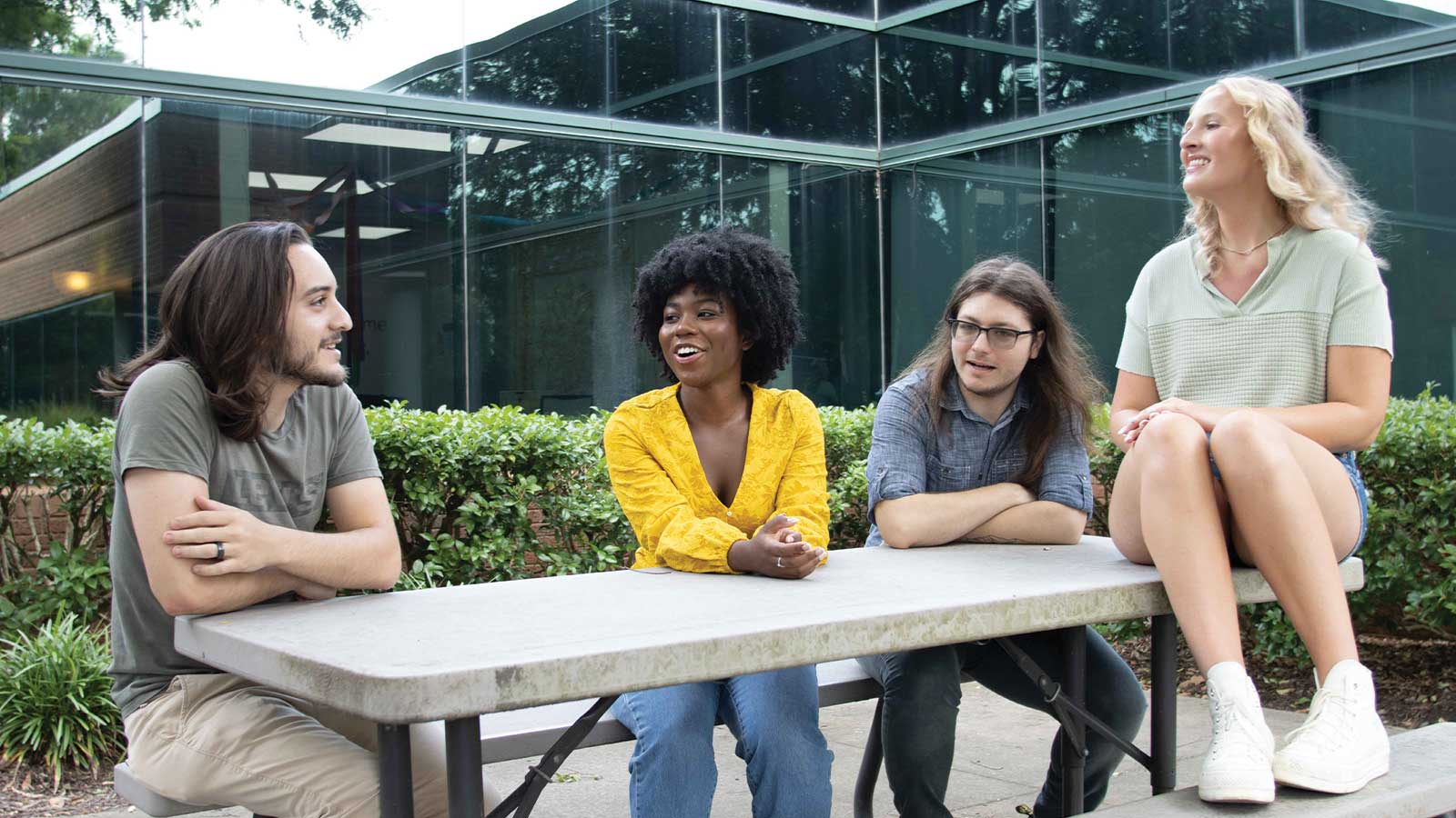 four young adults outside sitting at a table