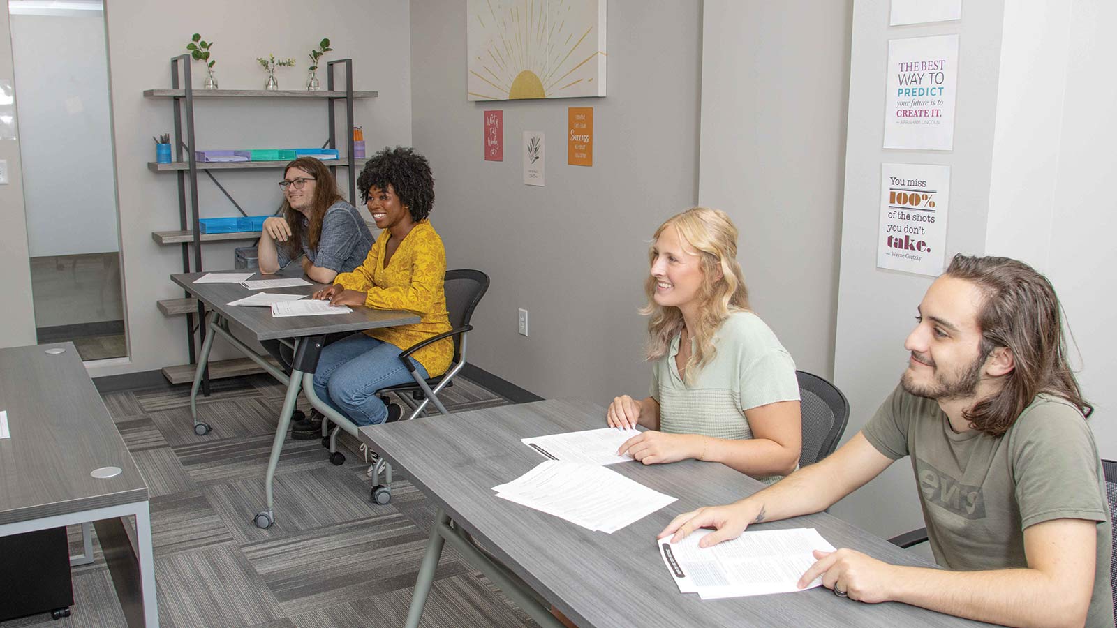 several people sitting at a table in a room with a laptop