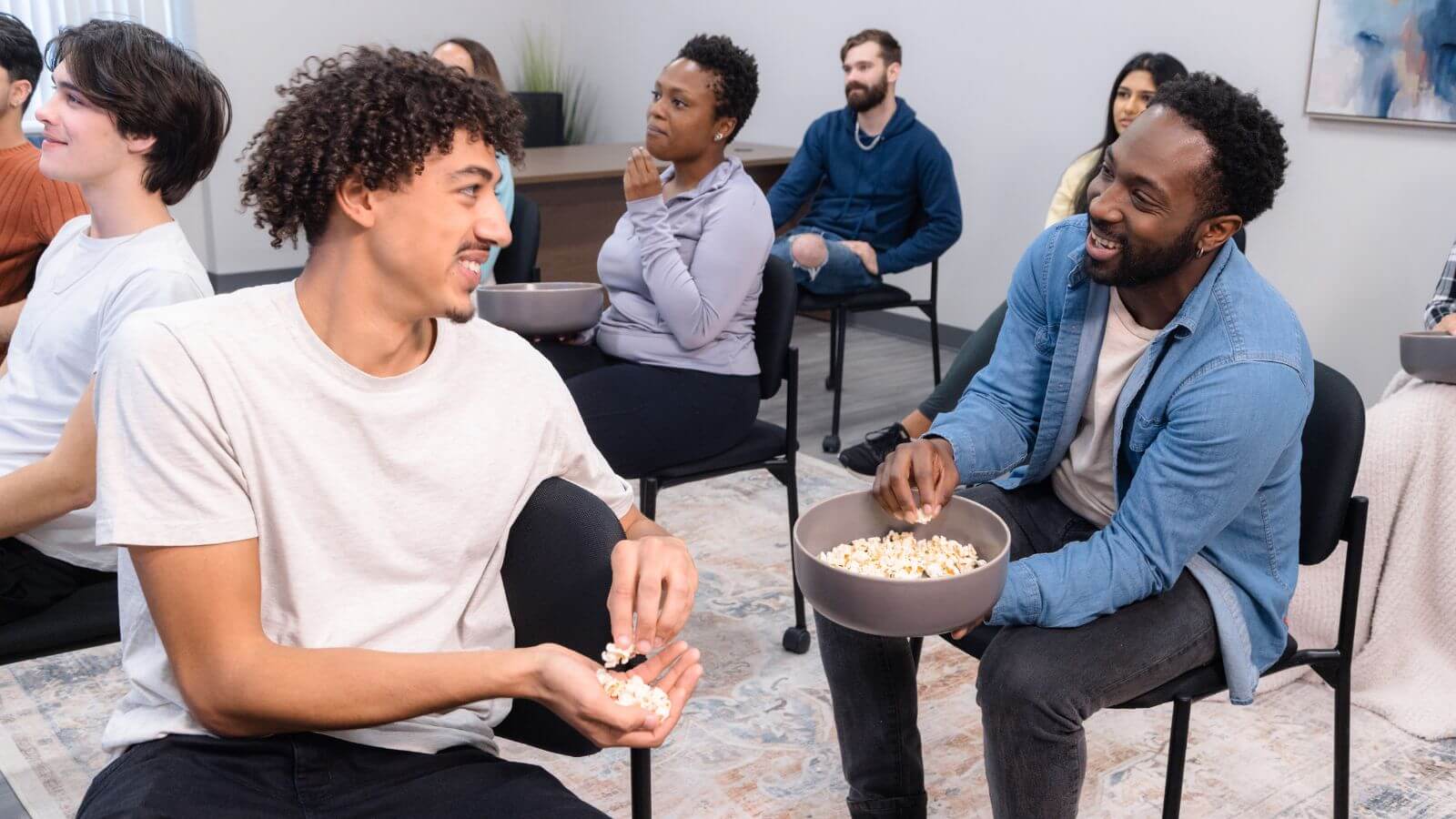 several people sitting in chairs watching a man eating popcorn