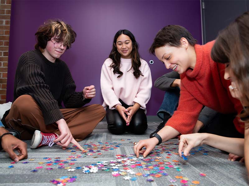 several people sitting on the floor playing with a puzzle