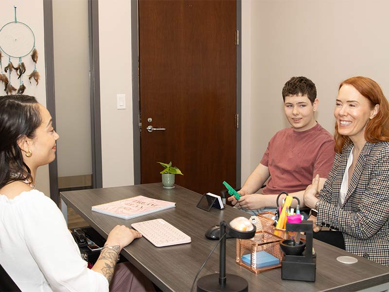 there are three people sitting at a table talking to each other