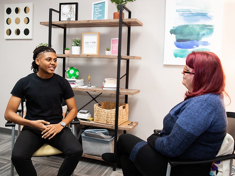 there are two women sitting in chairs talking to each other