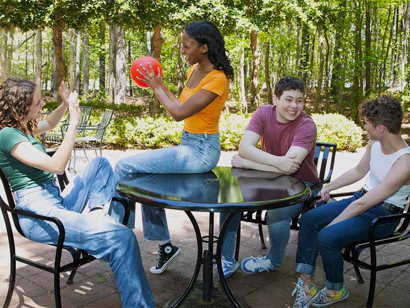 several people sitting around a table playing with a red ball