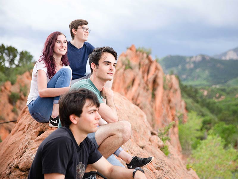 there are three people sitting on a rock together