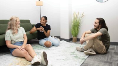 Three Young Adults Talking On Floor