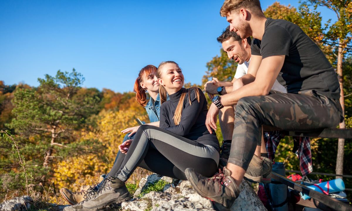 Group of travelers sitting on rock and resting after trekking in mountain