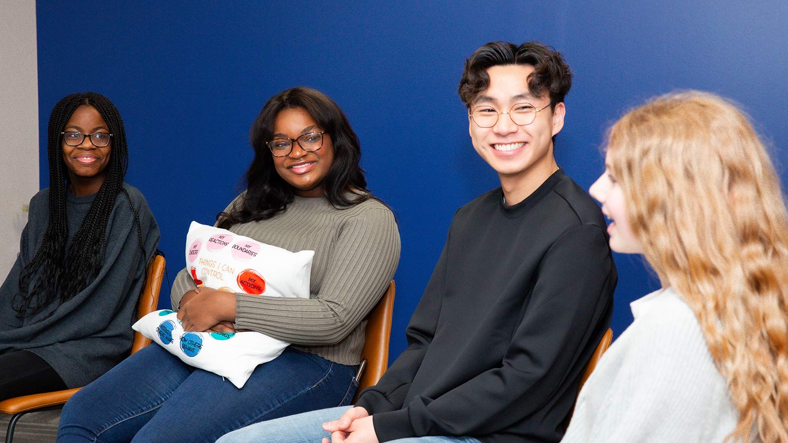 A group of four teenagers smiling at each other.