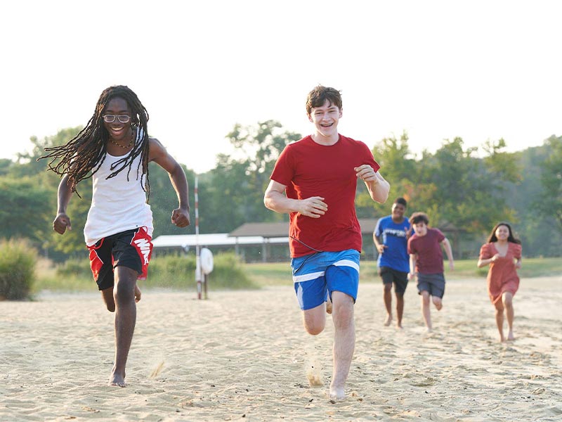 group of teenagers running on the beach having fun